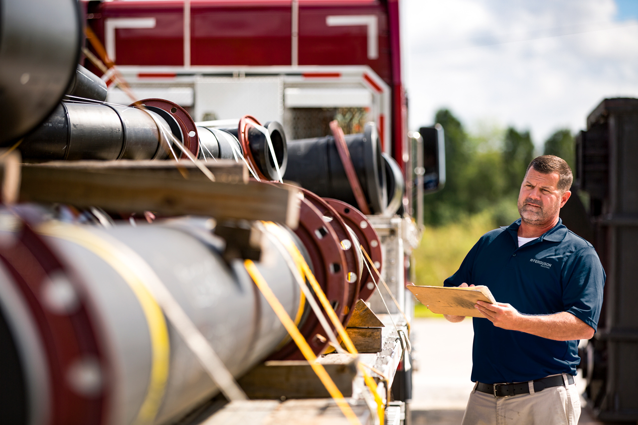 Ferguson associate inspecting an industrial parts delivery.