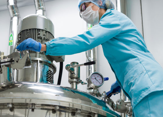 A professional from Duhig in clean, protective scrubs, working on a large sanitary product machine