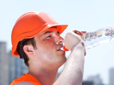 A man drinking water that is wearing emergency preparedness equipment.