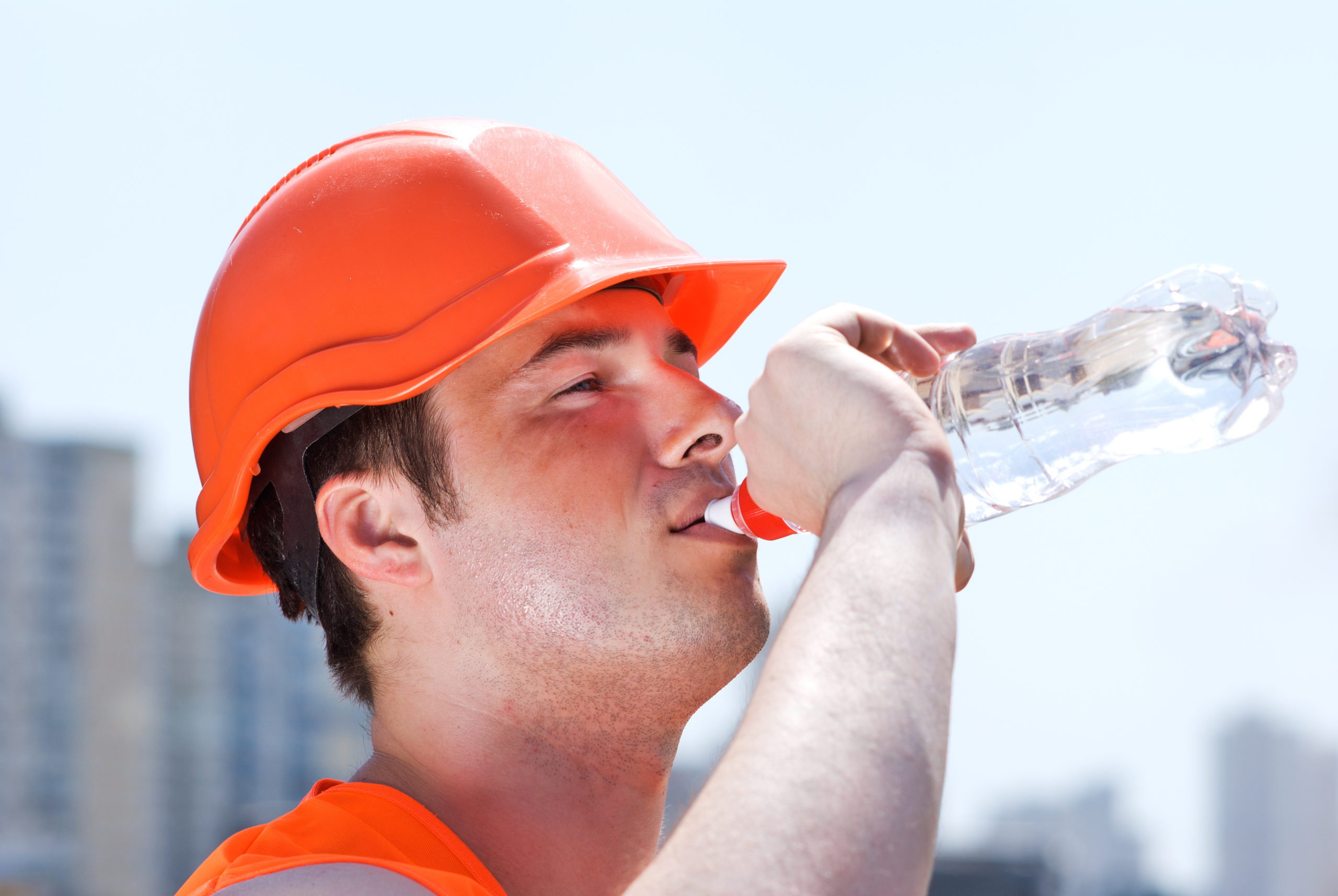 A man drinking water that is wearing emergency preparedness equipment.