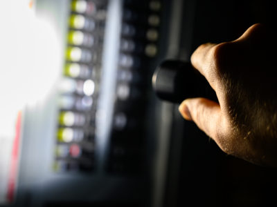 A person holding a flash light during a power outage aimed at a fuse box