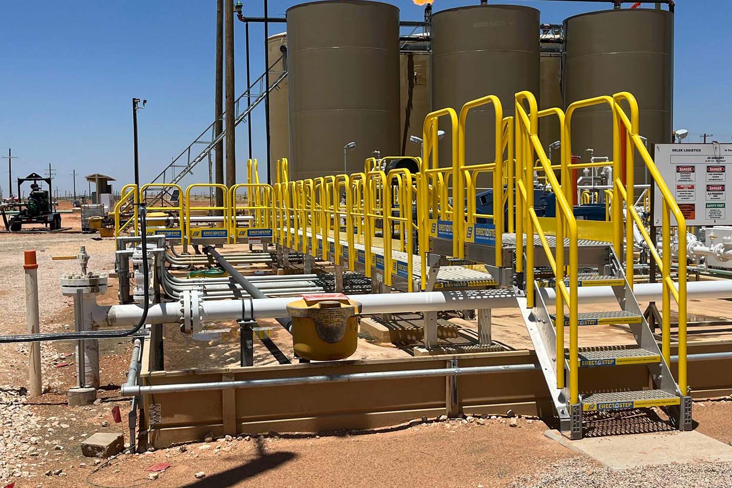 Industrial safety products such as a yellow hard hat, gray gloves, protective eye wear, vest, and black boots.