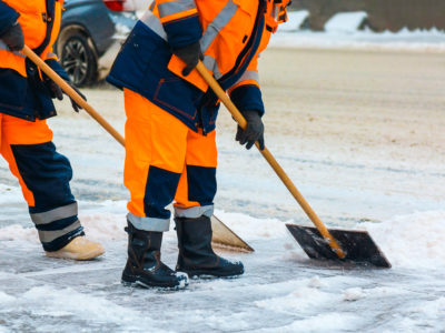 Emergency preparedness team sweeping snow from road in winter, cleaning city streets and roads after snow storm.