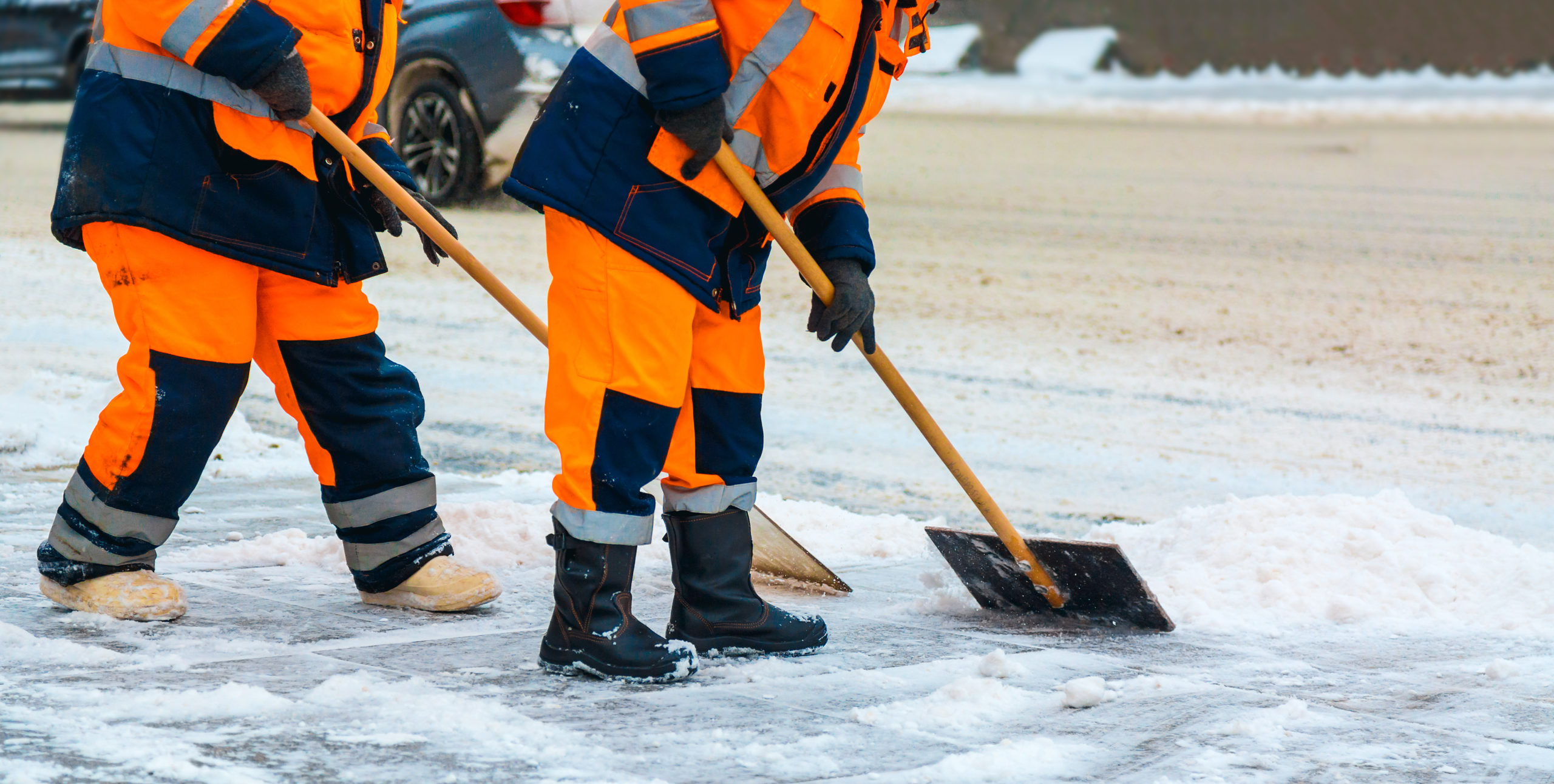 Emergency preparedness team sweeping snow from road in winter, cleaning city streets and roads after snow storm.