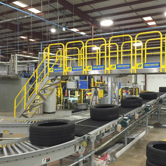 Erectastep stairs and platform that extend over an assembly line in a tire factory