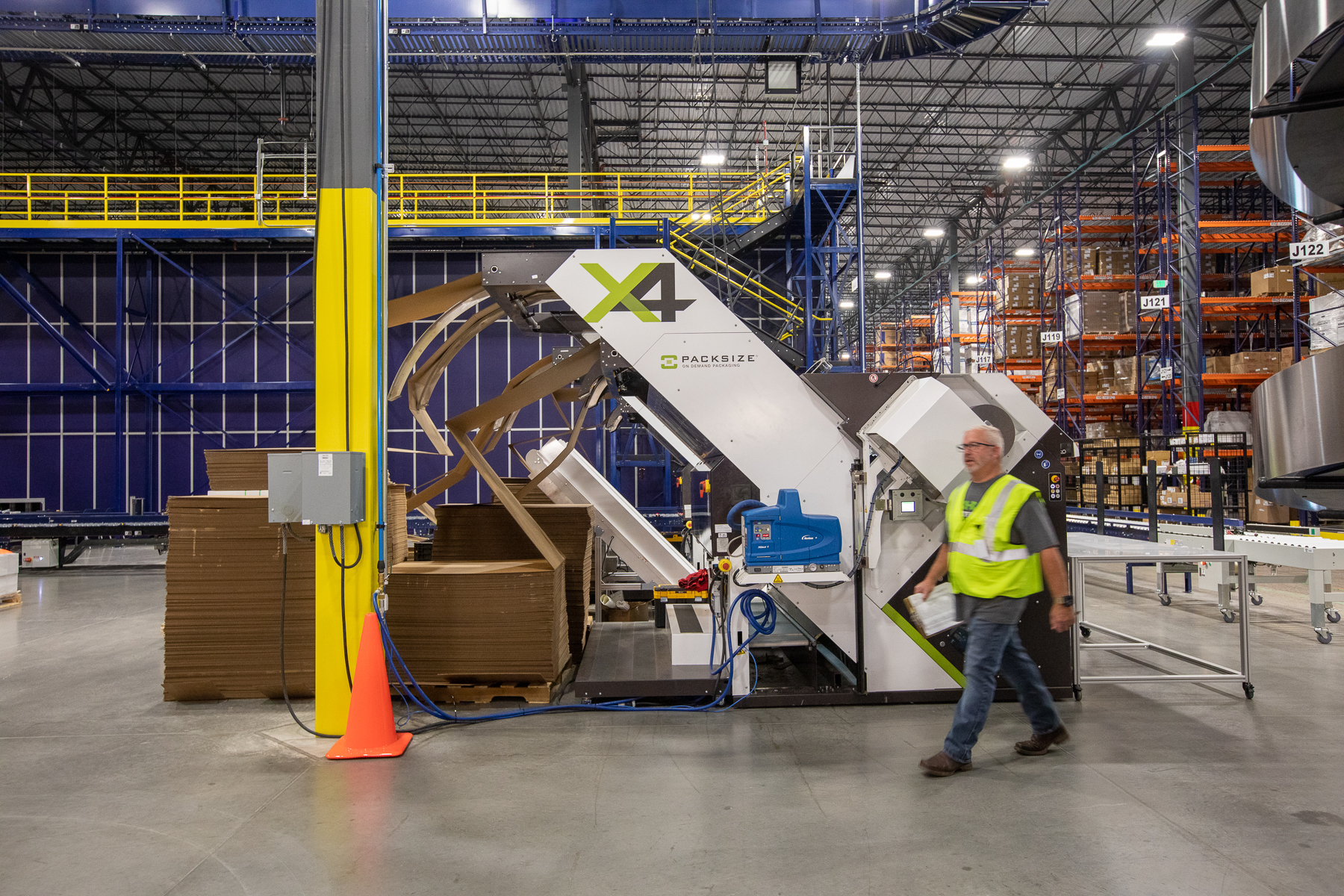 A distribution center with a man in a yellow vast walking past Ferguson Packaging Solutions.